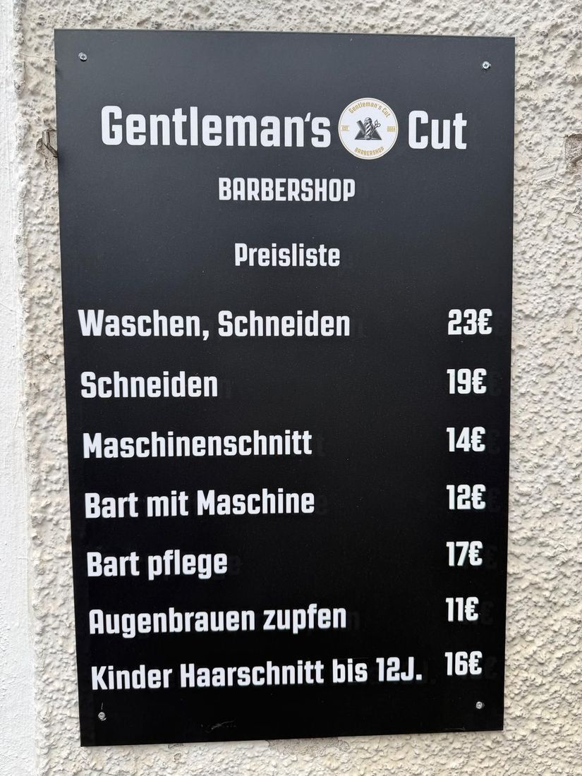 Schwarze Preistafel von Gentleman's Cut an der Fassade